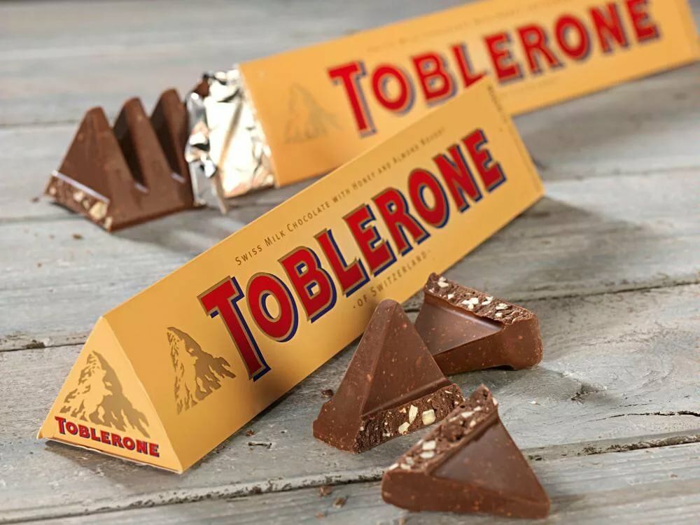 Шоколадные названия. Шоколад пирамидками Toblerone. Шоколад Toblerone конфеты. Швейцарский шоколад Тоблерон. Шоколад Toblerone молочный.